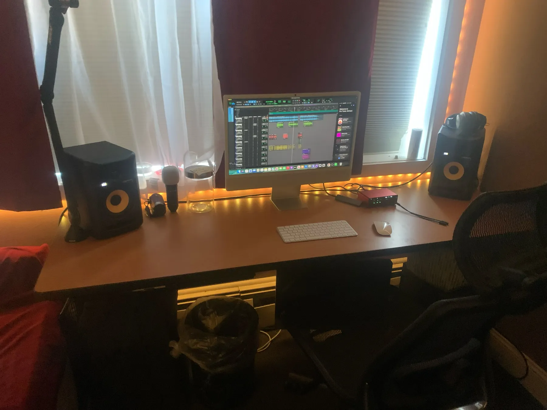 The Infinite Peace Records control room: an iMac on a long desk between KRK monitors, red curtains and an amber light strip